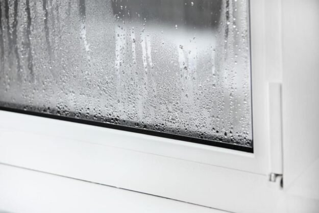 a plastic window with condensation of water on the glass Double glazed PVC window Concept: defective plastic window with condensation, temperature difference, cooling, humidity in the room